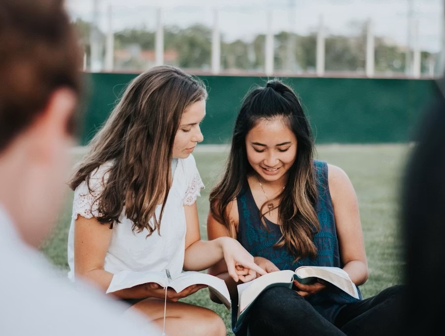 Two friends reading the Bible together outdoors
